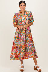 woman wearing a colorful floral print midi dress with short sleeves and a ruffled collar, standing and smiling