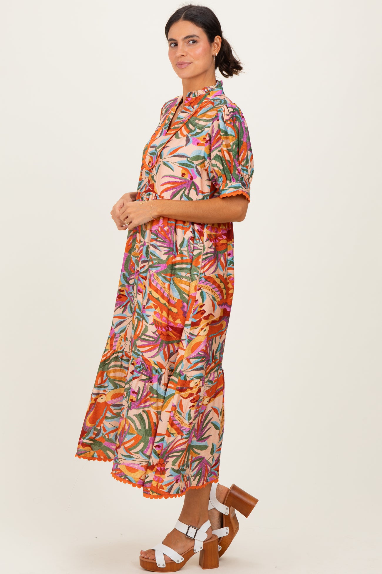woman wearing a colorful floral midi dress with short sleeves and tiered skirt, paired with brown platform heels