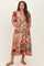 woman wearing a colorful floral maternity dress, smiling and cradling her baby bump