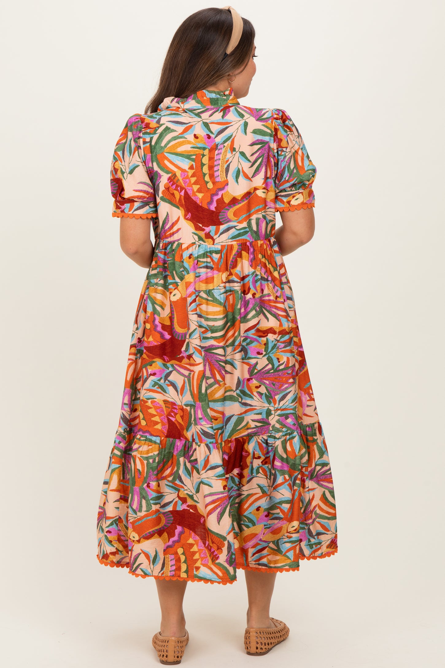 woman wearing a colorful floral print maternity maxi dress with puff sleeves and a tiered skirt from the back