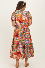woman wearing a colorful floral print maternity maxi dress with puff sleeves and a tiered skirt from the back