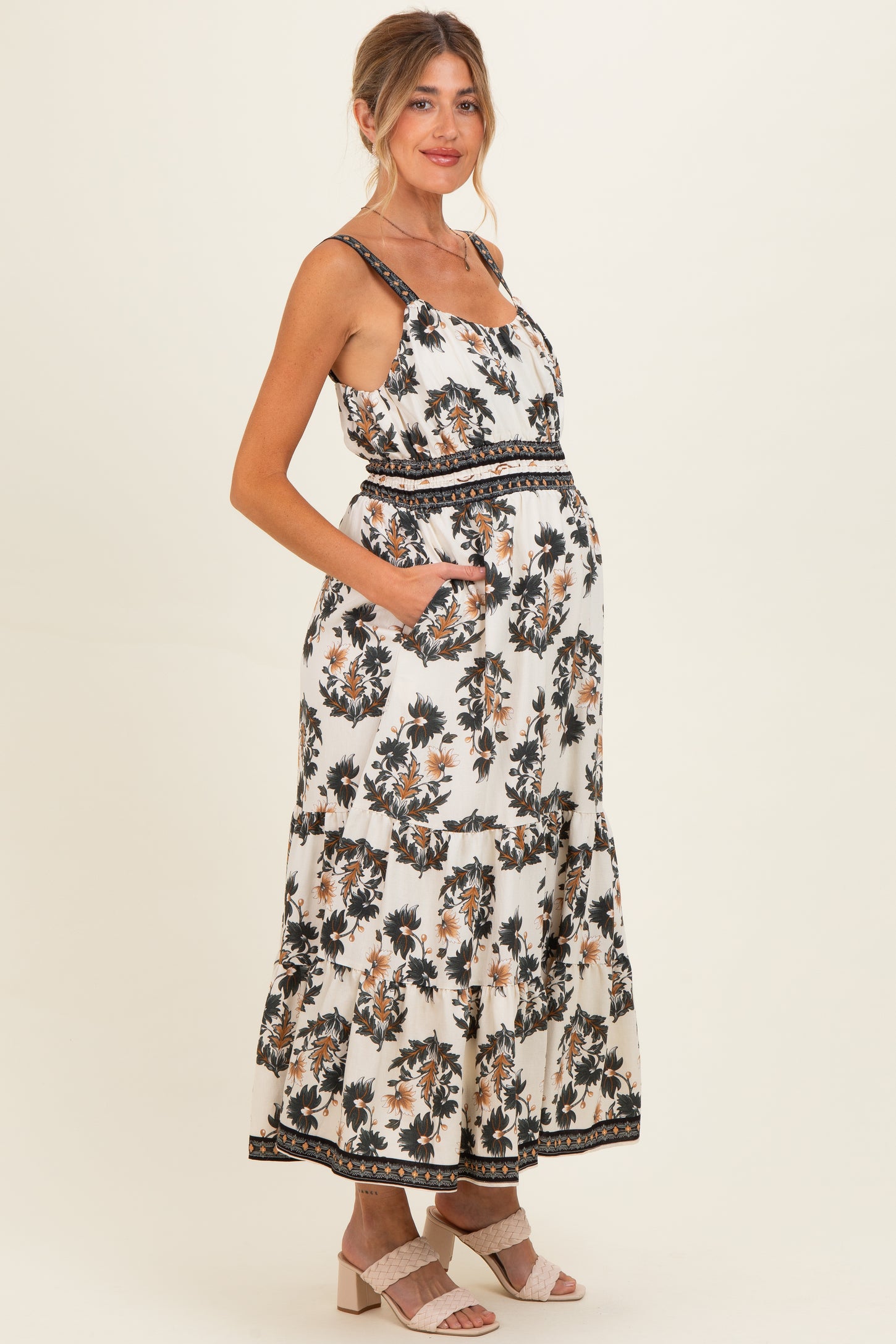 woman wearing a floral print white maternity maxi dress with pockets and a visible baby bump