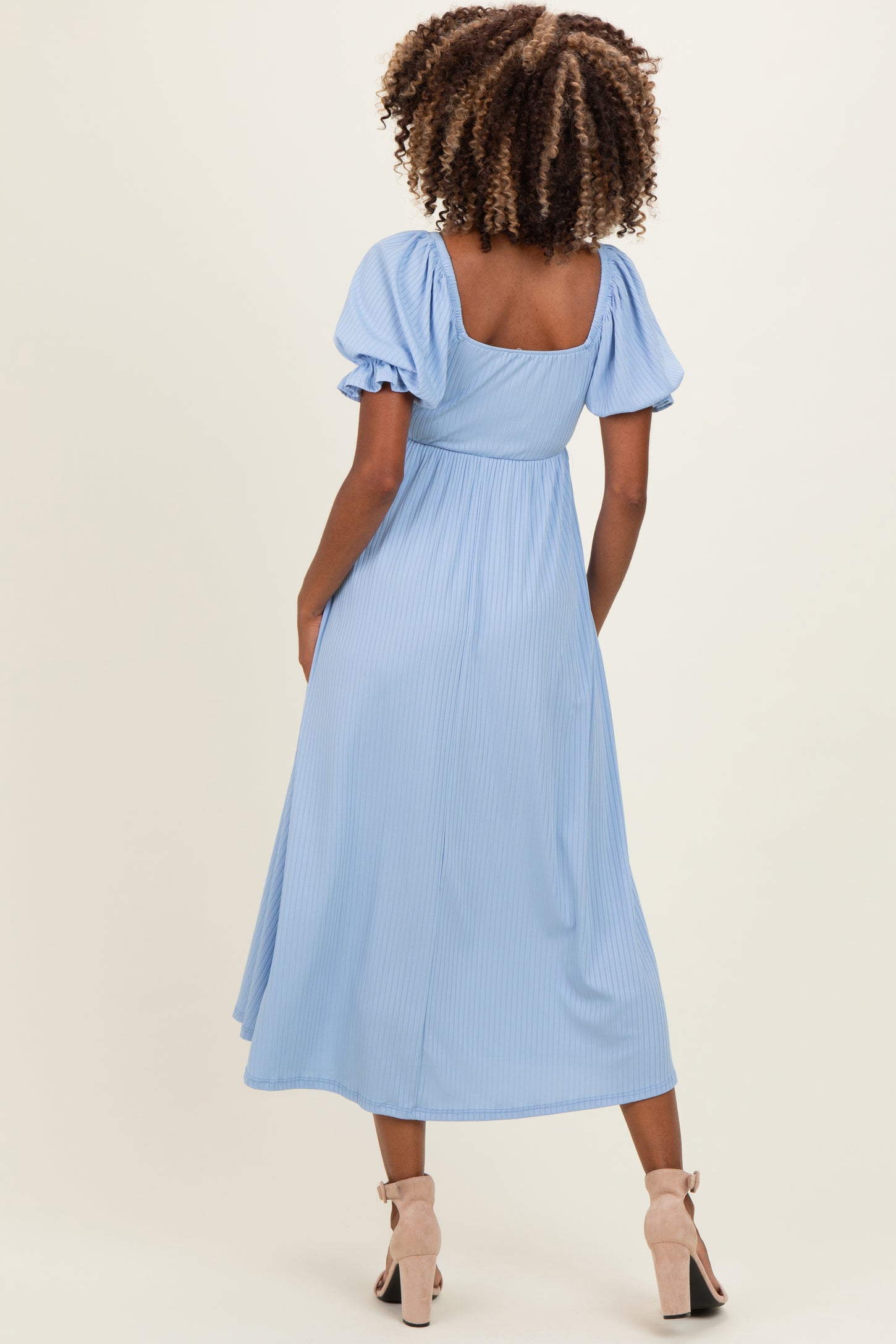 woman wearing a light blue striped maternity dress with puff sleeves and a fitted waist, seen from the back.