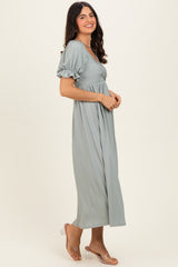woman wearing a long sage green ribbed maxi dress with puff sleeves and a fitted bodice, smiling sideways