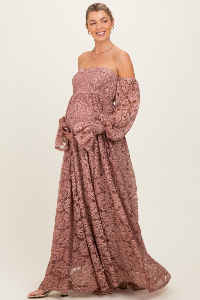 woman wearing a dusty rose off-shoulder lace maternity maxi dress with long puff sleeves and a visible baby bump