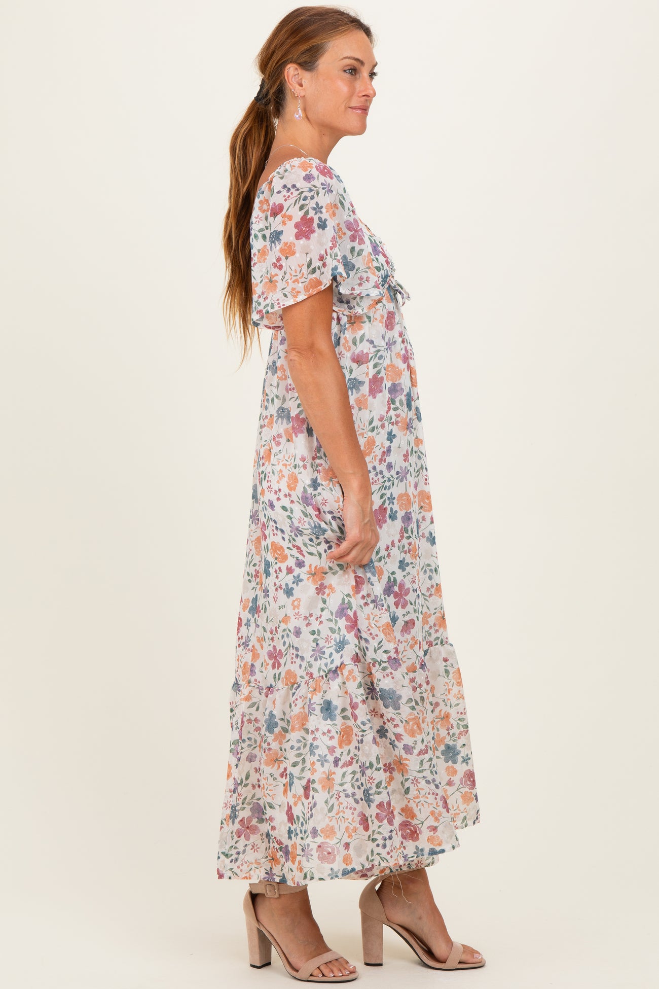 woman wearing a floral maxi dress with short sleeves and a cinched waist, standing sideways