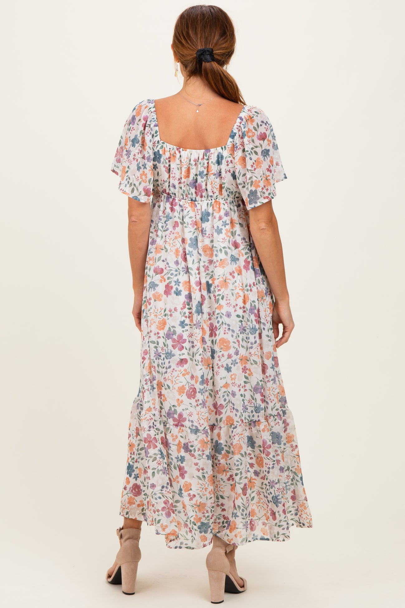 woman wearing a floral maxi dress with short flutter sleeves and a square neckline, view from the back