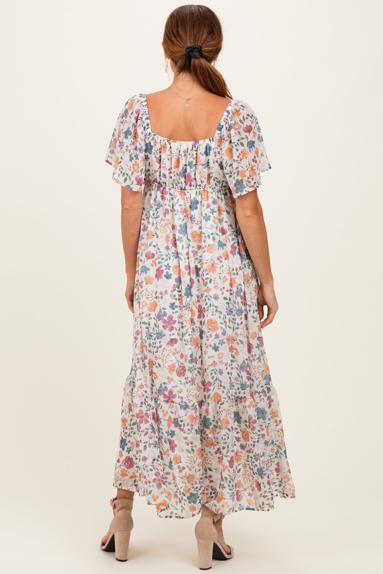 woman wearing a floral maxi dress with short flutter sleeves and a square neckline, view from the back