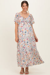 woman wearing a floral maternity maxi dress with a tie detail and short flutter sleeves, showcasing her baby bump