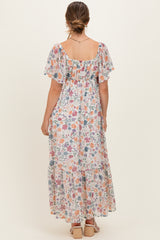 woman wearing a flowy floral maternity maxi dress with short flutter sleeves and a smocked back detail