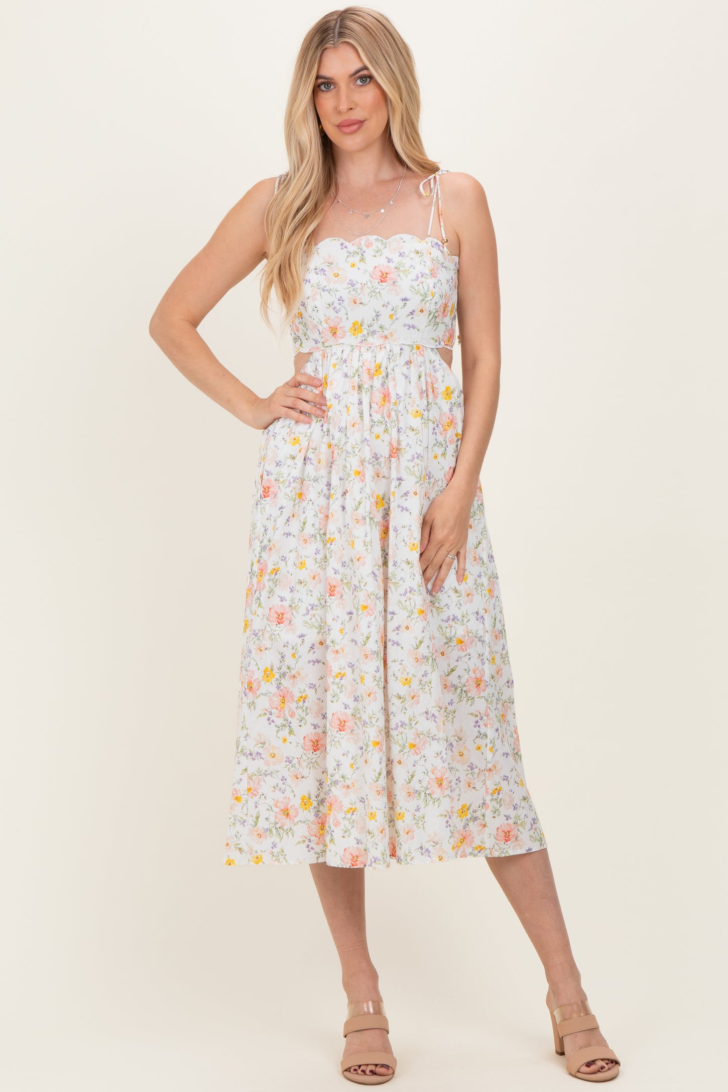 woman wearing a white floral midi sundress with adjustable spaghetti straps and a fitted bodice