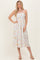 woman wearing a white floral midi sundress with adjustable spaghetti straps and a fitted bodice