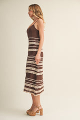 woman wearing a brown and beige striped knit midi dress with a fitted bodice and scalloped hemline