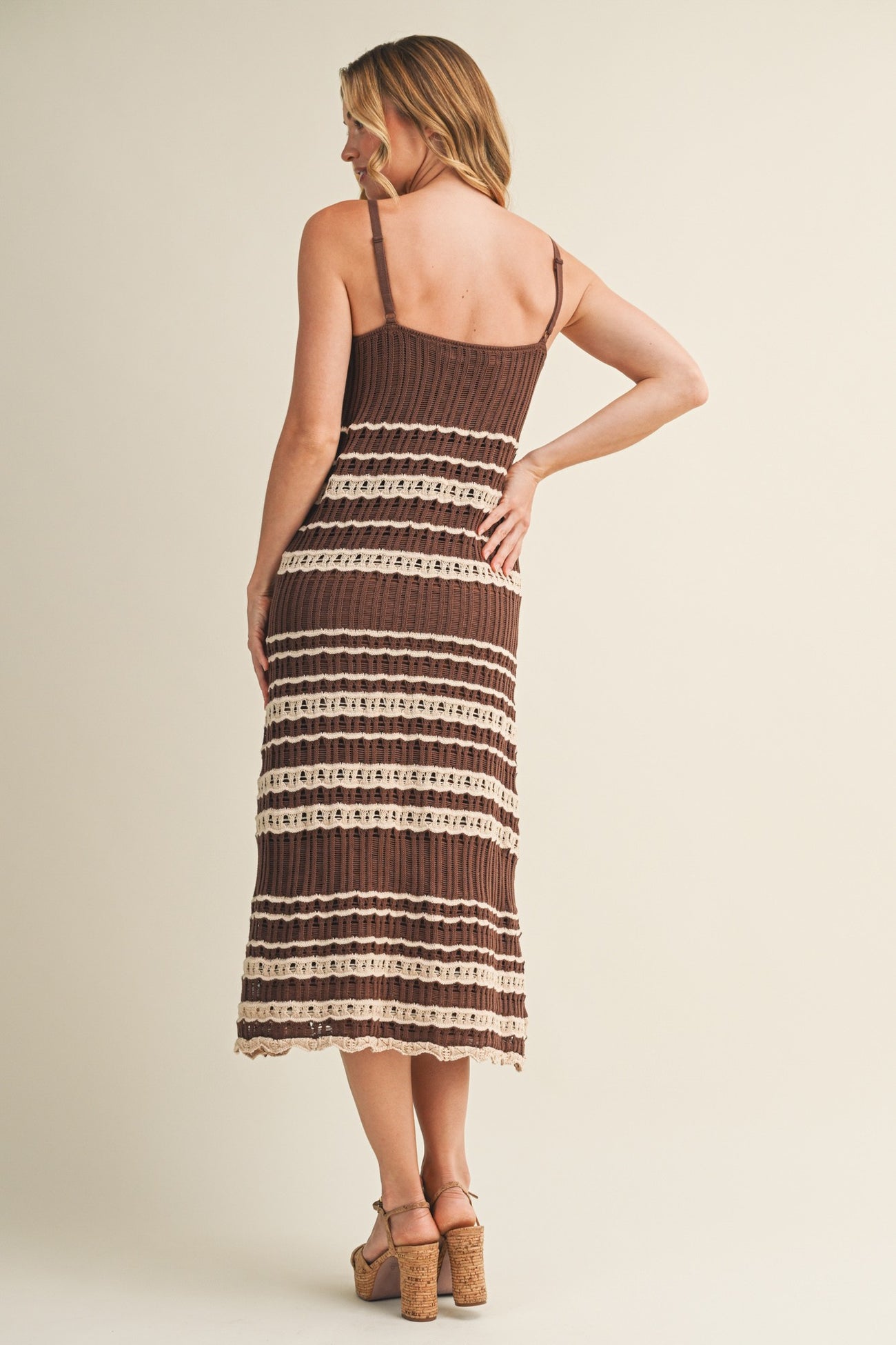 woman wearing a brown striped midi dress with lace details and thin straps, shown from the back