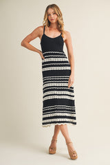 woman wearing a black and white striped knit maxi dress with spaghetti straps and lace trim details