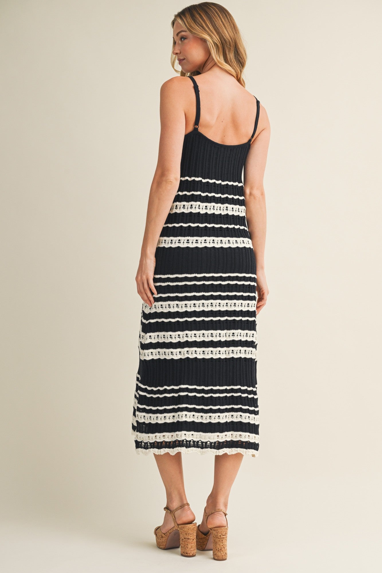 woman wearing a black and white striped midi dress with a fitted bodice and spaghetti straps