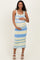 woman wearing a striped yellow and blue maternity dress, smiling and holding her baby bump