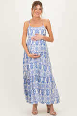 woman wearing a blue and white patterned maternity maxi dress and holding her baby bump
