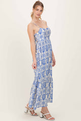 woman wearing a blue and white patterned maxi dress with spaghetti straps and a ruffled hem