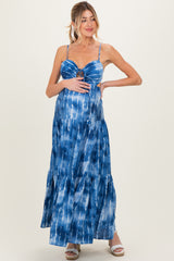 woman wearing a blue tie-dye maternity maxi dress with a fitted bodice and tiered skirt, showing her baby bump
