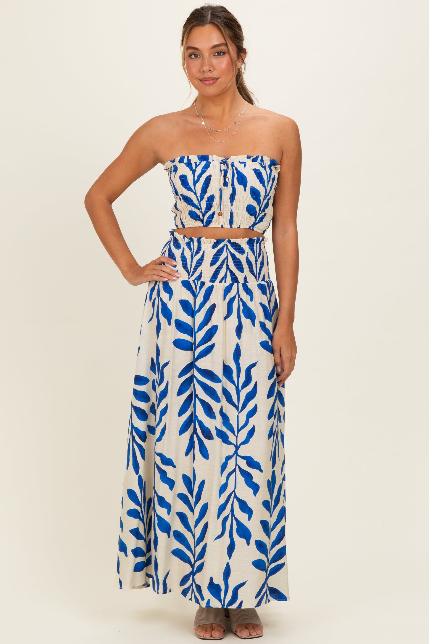 woman wearing a strapless maxi dress with a blue leaf print and a matching belted waist