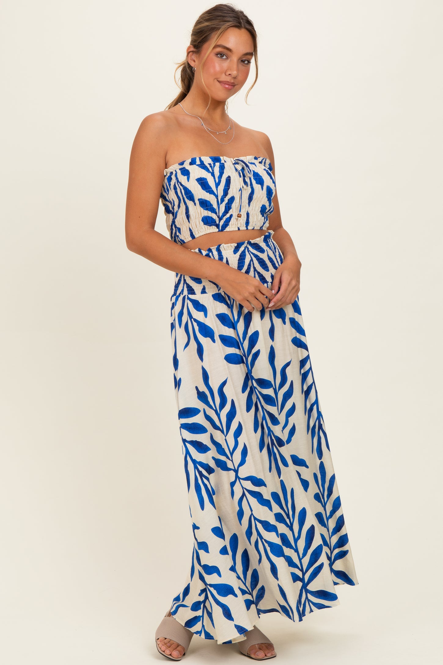 woman wearing a strapless crop top and matching maxi skirt with a blue leaf print pattern