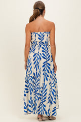 woman wearing a strapless maxi dress with a blue leaf print on a white background, showing the back view