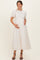 woman wearing a white lace maternity dress with short sleeves and a flowy skirt, gently holding her baby bump