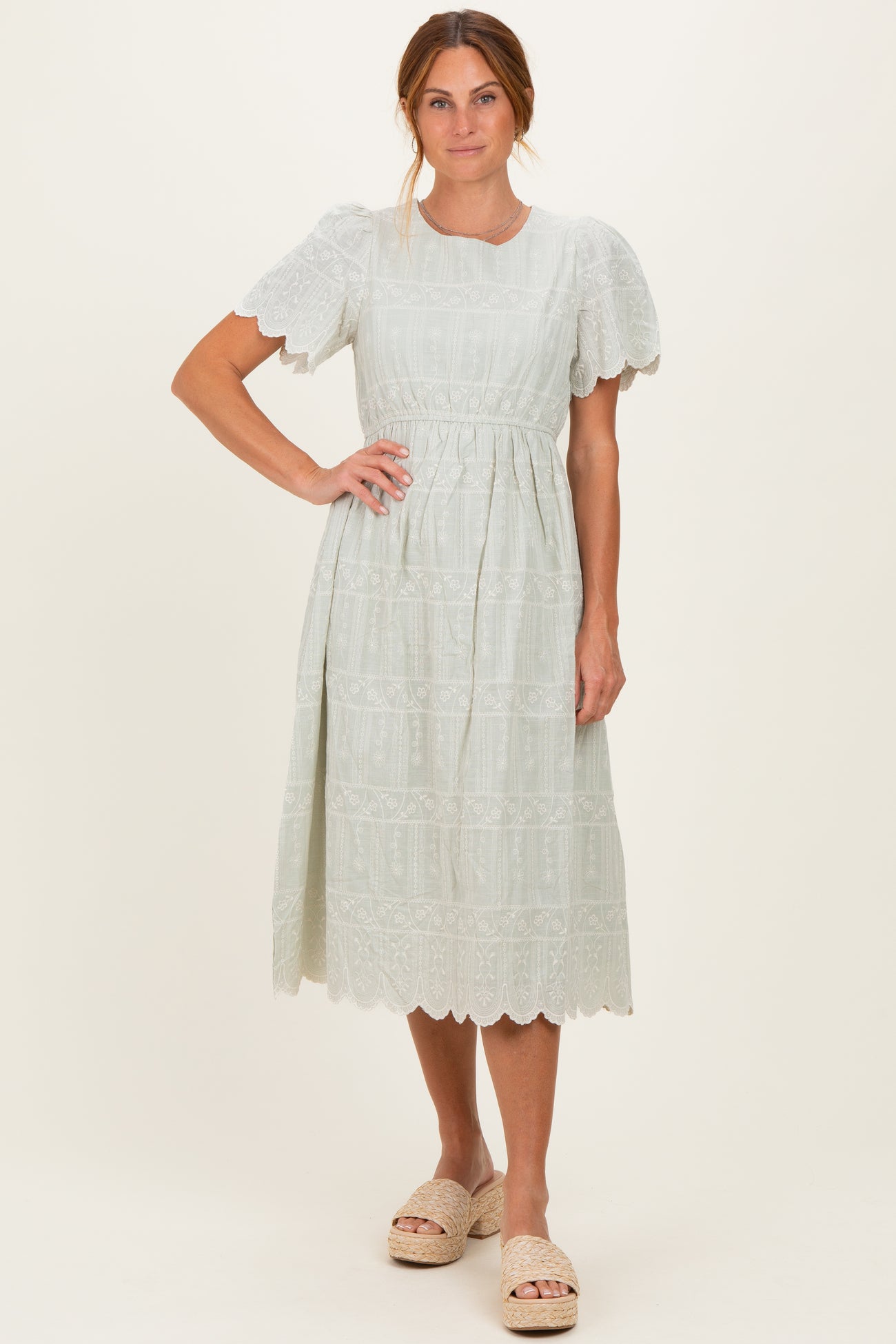 woman wearing a light green midi dress with puff sleeves and lace detailing, paired with cream-colored sandals