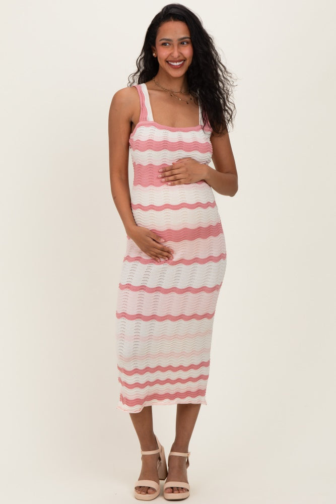 woman wearing a pink and white striped maternity dress, smiling and holding her baby bump