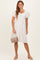 woman wearing a white short puff sleeve dress with a square neckline, holding a light beige handbag