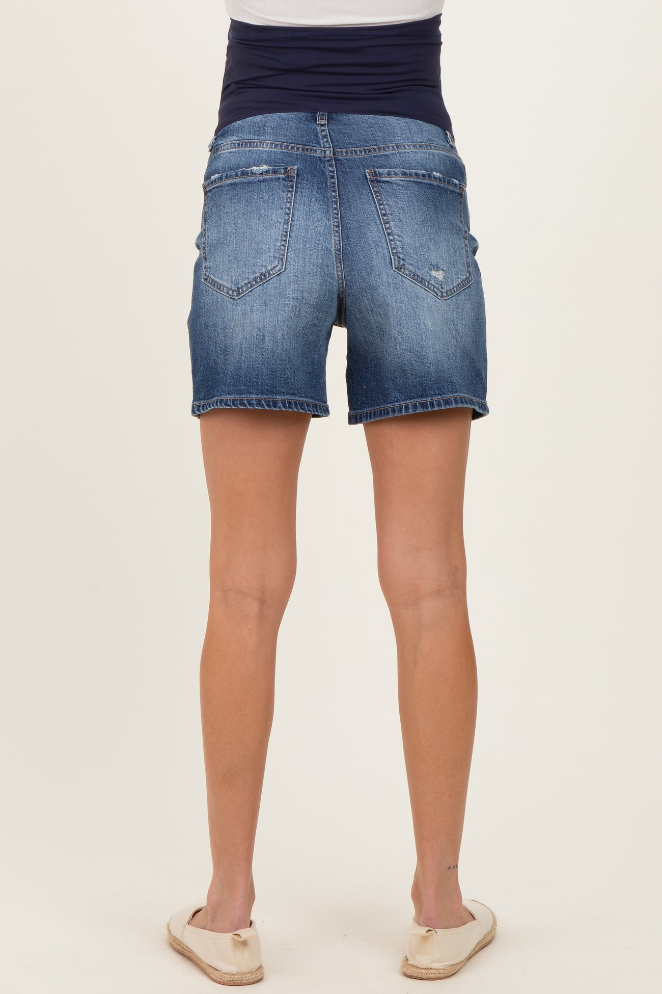 woman wearing dark blue maternity denim shorts with a stretchy waistband, view from the back