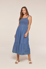 woman wearing a denim maxi dress with a smocked bodice and tiered skirt, standing against a neutral background