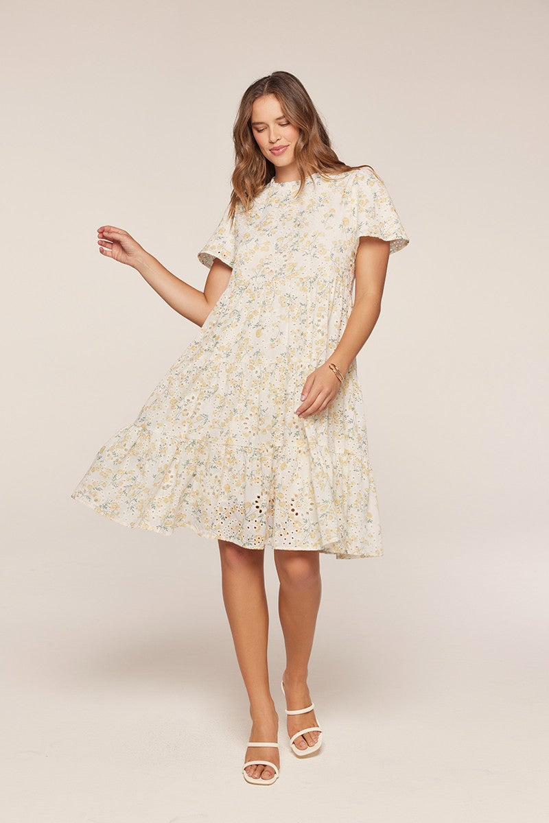 woman wearing a light floral short sleeve dress with a tiered skirt and eyelet details