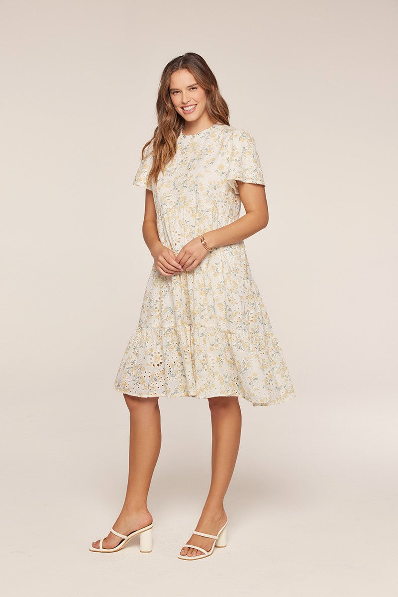woman wearing a light yellow floral fit-and-flare dress with short sleeves and tiered skirt