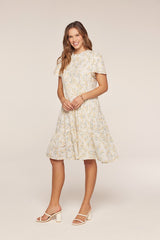 woman wearing a light yellow floral fit-and-flare dress with short sleeves and tiered skirt