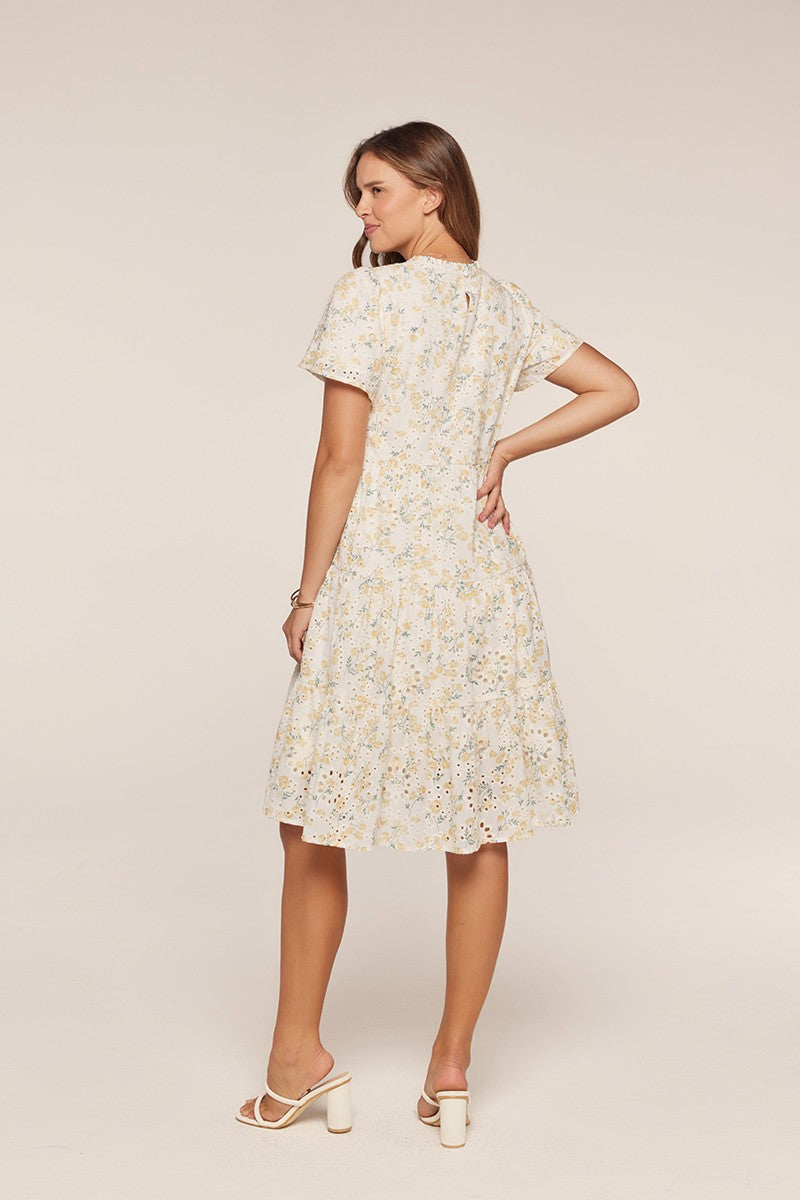 woman wearing a white floral short sleeve dress with a flared skirt and eyelet detailing, shown from the back