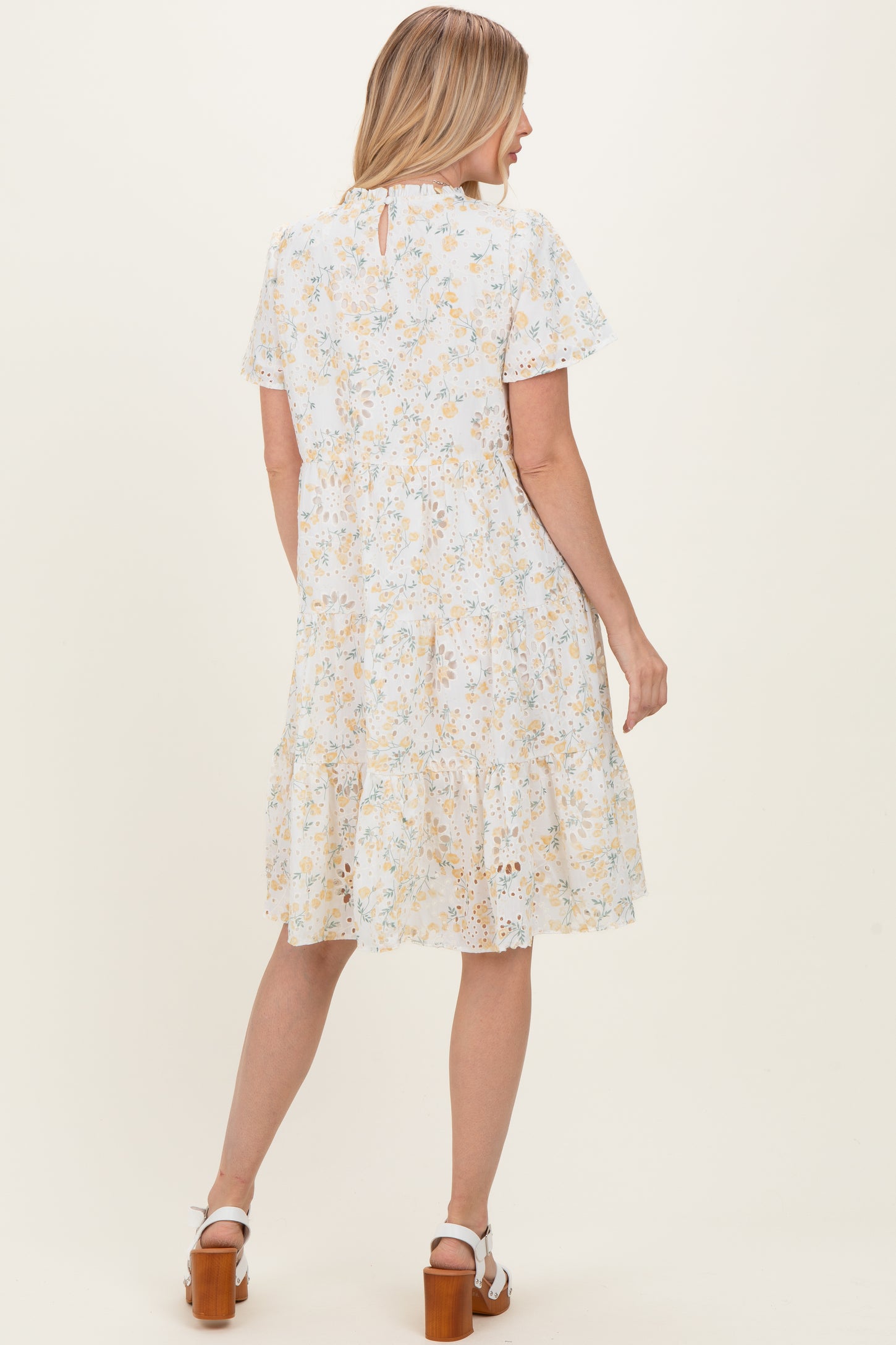 woman wearing a light blue floral short sleeve dress with a tiered skirt and a keyhole back detail