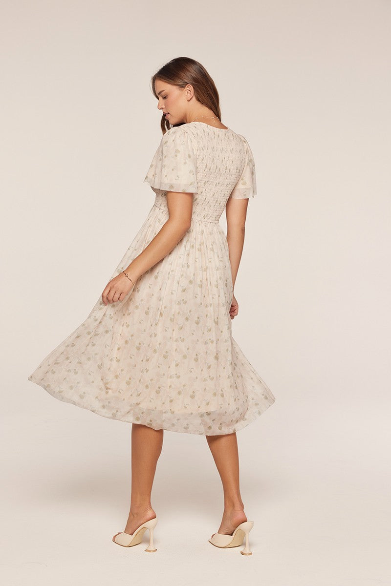 woman wearing a cream floral midi dress with short sleeves and a smocked back detail