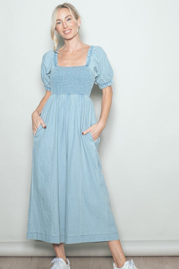 woman wearing a light blue smocked maxi dress with puff sleeves and pockets, styled with white sneakers