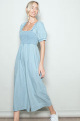 woman wearing a light blue smocked waist midi dress with puff sleeves and side pockets