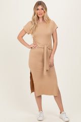 woman wearing a beige short sleeve midi dress with a tied waist detail and side slits, paired with white sneakers