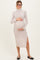 woman wearing a beige ribbed maternity dress with a high neckline and side slit, holding her baby bump