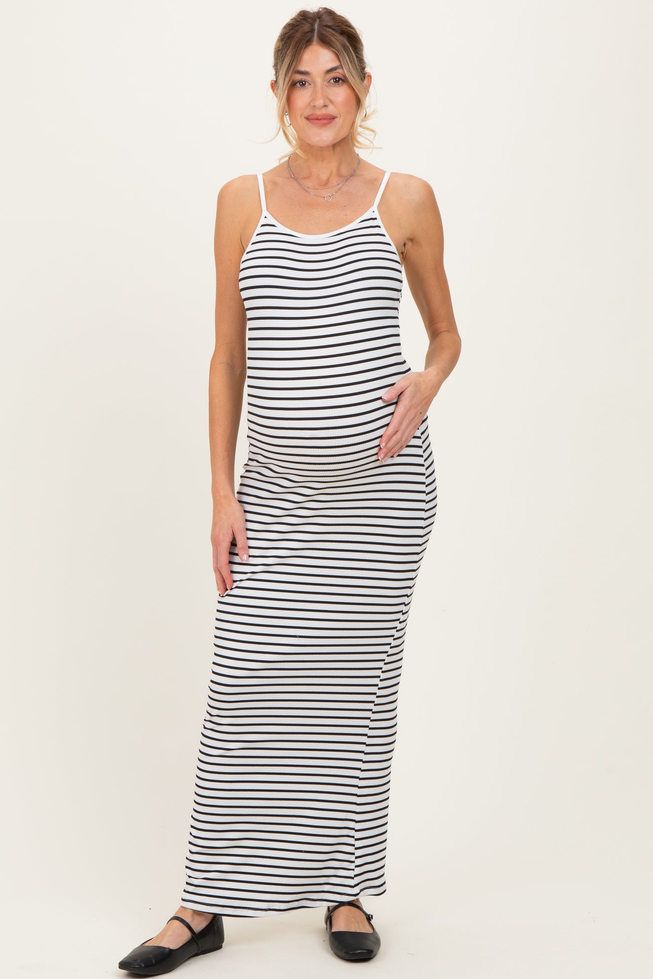woman wearing a black and white striped maternity maxi dress and holding her baby bump