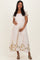 woman wearing a cream maternity dress with floral embroidery and puff sleeves, holding her baby bump