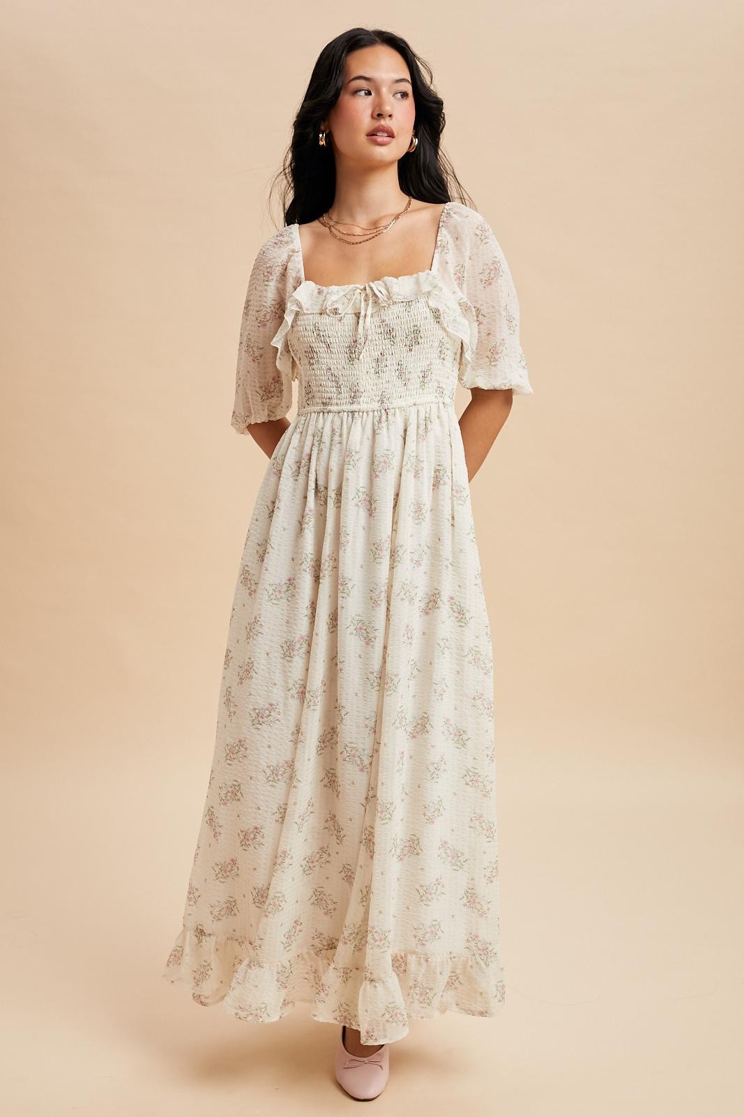 woman wearing a cream floral maxi dress with puff sleeves and smocked bodice