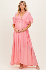woman wearing a light pink maternity maxi dress with ruffle sleeves and a button-down front, holding her baby bump