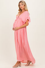 woman wearing a pink v-neck short sleeve maternity maxi dress, cradling her baby bump