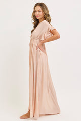 woman wearing a light pink maxi dress with ruffles on the sleeves and a cinched waist