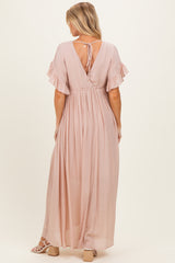 woman wearing a blush pink maternity maxi dress with flutter sleeves and a tie-back detail